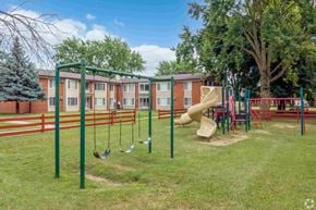 Sterling Heights apartment for rent - a playground with a slide and swings in front of an apartment building