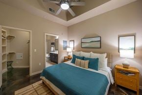 Houston apartment for rent - A bedroom with a bed, nightstand, and a painting on the wall.