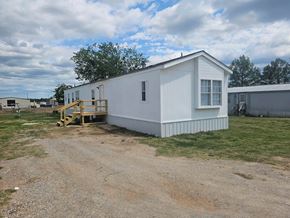 Shawnee house for rent - A white house with a porch is situated in a grassy area.