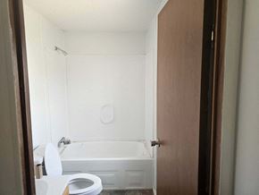 Shawnee house for rent - A white toilet is in a small bathroom with a white tub.