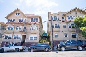 Oakland apartment for rent - A row of apartment buildings with cars parked in front.