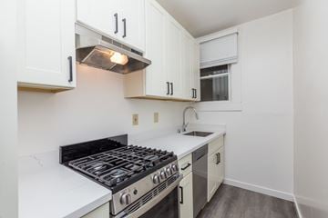 Oakland apartment for rent - A kitchen with a stove top oven and white cabinets.