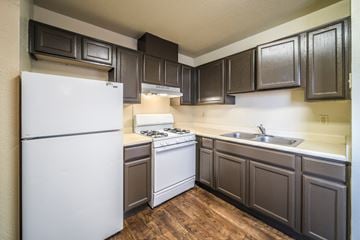 El Paso apartment for rent - A kitchen with a white refrigerator and dark brown cabinets.