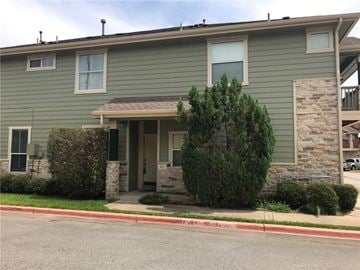 Round Rock apartment for rent - A green house with a stone pillar on the front porch.