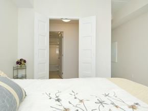 Ottawa apartment for rent - A bedroom with a large bed and a doorway leading to another room.