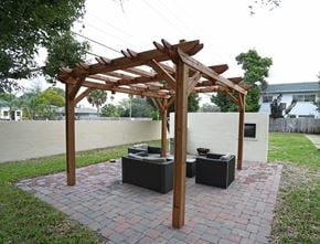 Clearwater apartment for rent - A wooden pergola with two benches is situated on a brick patio.