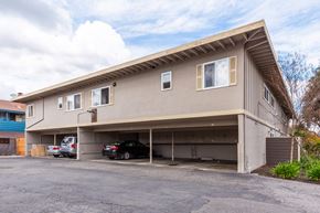 Sunnyvale apartment for rent - the front of a building with a parking lot and two cars