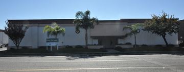 Torrance apartment for rent - A building with a white facade and a green sign in front.