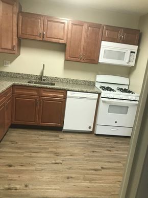 Baltimore apartment for rent - A kitchen with white appliances and wooden cabinets.