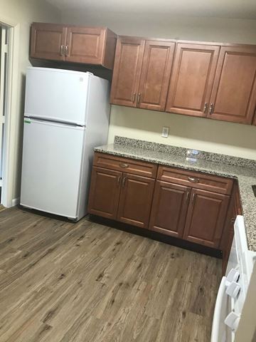 Baltimore apartment for rent - A white refrigerator in a kitchen with wooden cabinets.