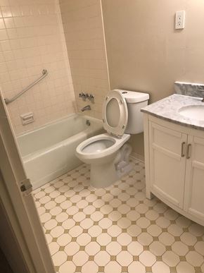 Baltimore apartment for rent - A white toilet is installed in a bathroom with a white tiled floor and walls.