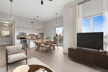 Houston apartment for rent - A modern living room with a large flat screen TV and a dining table with chairs.