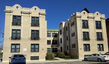 Forest Park apartment for rent - A tan building with a green roof and a car parked in front.