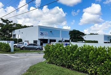 Pompano Beach apartment for rent - A white building with a blue sign on it and a car parked in front.