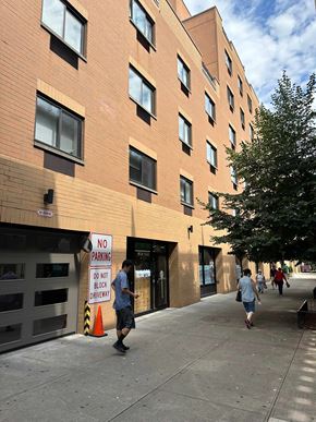 Astoria apartment for rent - A man walks past a no parking sign on a sidewalk.
