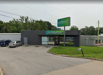 Independence apartment for rent - a building with a green sign and a parking lot with cars