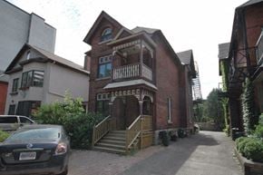 Ottawa apartment for rent - A car is parked in front of a brick building with a balcony.