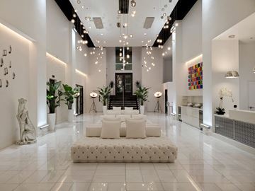 Chamblee apartment for rent - A white living room with a large white sofa and a glass staircase.