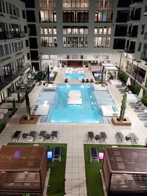 Chamblee apartment for rent - A large swimming pool surrounded by lounge chairs and potted plants.