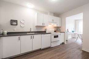 Ottawa apartment for rent - a kitchen with white cabinets and appliances and a dining room
