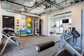 Sacramento apartment for rent - a gym with weights and other exercise equipment on the wall and a television
