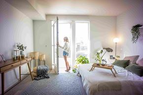 Sacramento apartment for rent - a woman opening a sliding glass door in a bedroom