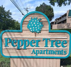 Springfield apartment for rent - A sign for Pepper Tree Apartments with a blue background and a tree design.
