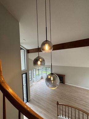 Carlsbad house for rent - Three spherical pendant lights are suspended from the ceiling in a spacious room with a wooden staircase.