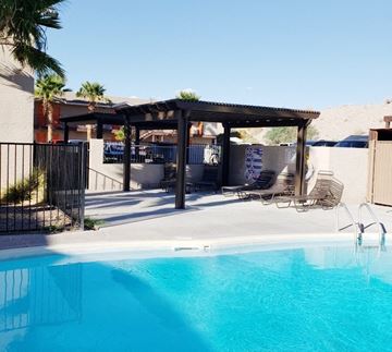 Bullhead City apartment for rent - A pool with a black fence and a black and white striped umbrella.