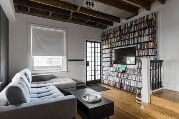 Narberth house for rent - A living room with a grey couch and a wall of DVDs.