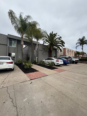 San Diego apartment for rent - A parking lot with cars and palm trees in front of a building.