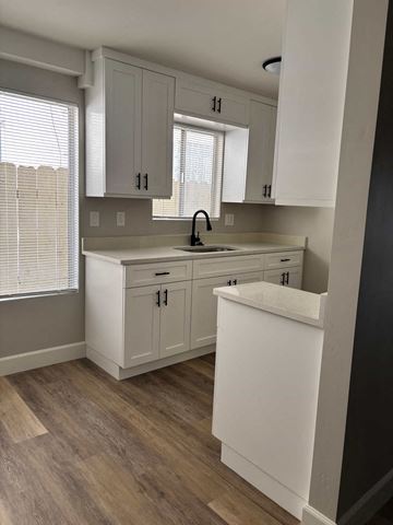 San Diego apartment for rent - A kitchen with white cabinets and a wooden floor.