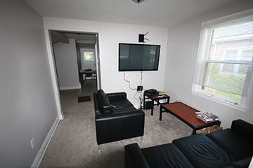 Hamilton apartment for rent - A living room with a black couch and a television.
