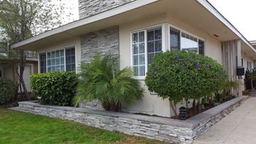Newport Beach apartment for rent - the front of a house with a stone wall and plants