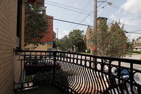 Pittsburgh apartment for rent - A balcony with a metal railing and a bench overlooks a street.
