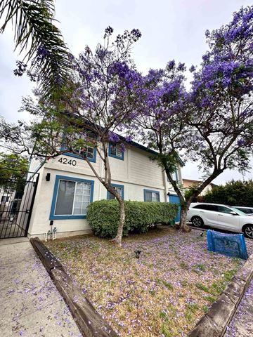 San Diego apartment for rent - A white house with a blue door and a tree with purple flowers in front.