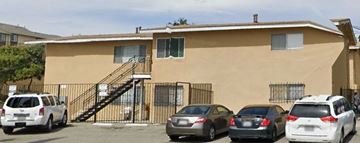 San Diego apartment for rent - A beige house with a black gate and a car parked in front.