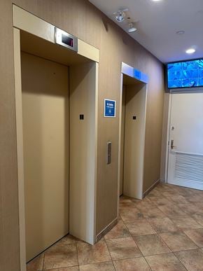 Astoria apartment for rent - Two elevators with a blue sign on the right one.