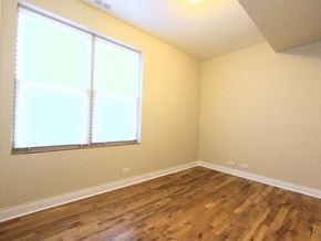 Chicago apartment for rent - A room with wooden floors and a window with blinds.