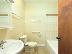 Chicago apartment for rent - A white toilet sits in a bathroom next to a sink and a bathtub.