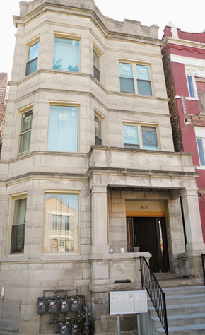 Chicago apartment for rent - A building with a black door and windows with white curtains.