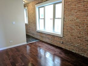 Chicago apartment for rent - A room with a brick wall and wooden flooring.