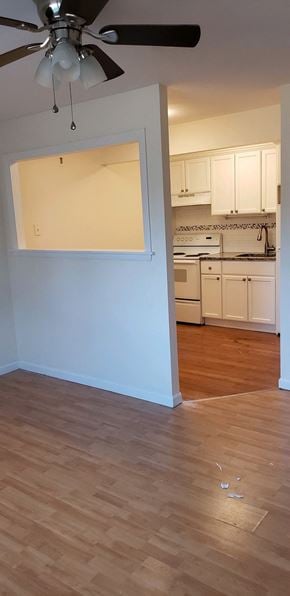 Milford apartment for rent - an empty living room and kitchen with wood flooring and a ceiling fan