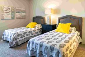 Comstock Park apartment for rent - a bedroom with two beds with yellow pillows and a night stand