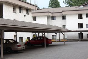 Spokane apartment for rent - a parking lot in front of a white building with cars parked in it