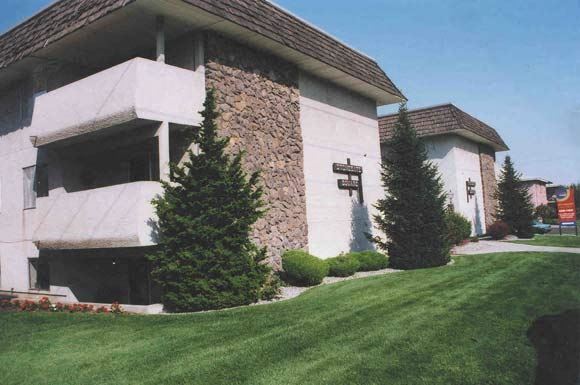 Spokane apartment for rent - a white building with two pine trees in front of it