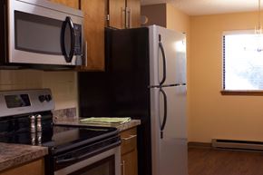 Spokane Valley apartment for rent - A kitchen with a black refrigerator and a black stove top oven.