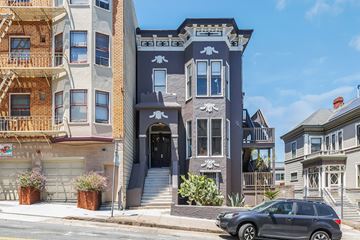 San Francisco apartment for rent - A grey car is parked in front of a two-story building with a balcony.