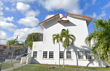 Miami apartment for rent - A white house with a red roof and a fence in front.