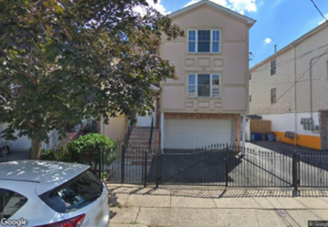 Newark apartment for rent - A two-story house with a garage is surrounded by a black fence.